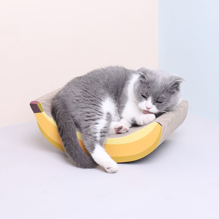 A cat lying comfortably on the Banana Shaped Cat Scratching Pad.